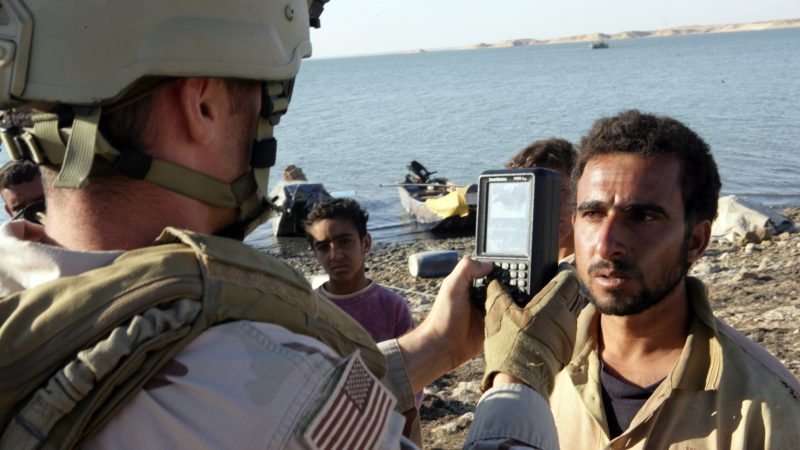 U.S. military member using a handheld biometric scanner to take a subjects iris scan